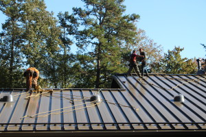 Harnessed workers on roof with skylights